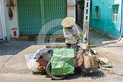 A garbage collector collecting carton boxes on a small street, Saigon, Vietnam Editorial Stock Photo