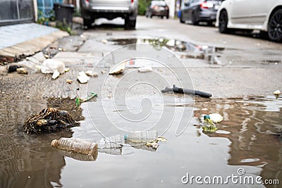 Garbage and dirty water,lot of rubbish scattered all over the street after heavy rains and flooding,dirt of debris,pieces of waste Stock Photo