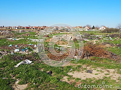Garbage dump near the village. Chaotic unofficial dump. Plastic, bags, paper, glass, biological waste. Green grass next to dirt. Editorial Stock Photo