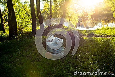 Garbage left by vacationers on the shore of the lake in the grass in plastic garbage bags. Pollution of nature. Non Stock Photo