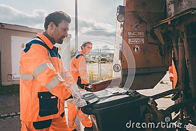 Garbage man and women cleaning dustbins into waste truck Stock Photo