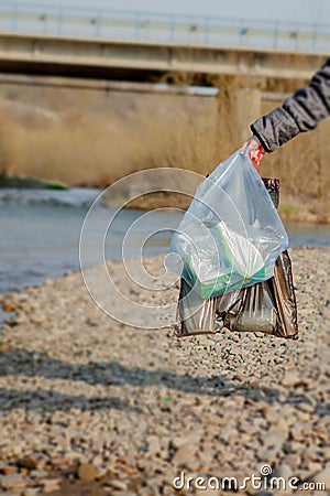 Garbage in the nature, cleaning the environment in the spring on the river from the rubbish a woman in disposable latex blue Stock Photo