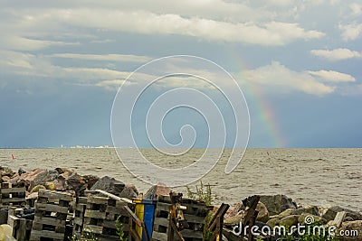 Garbage on the shore of the pond of the sea on the horizon city and rainbow Stock Photo