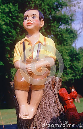 Garden art sculpture of boy sitting on wooden stump Stock Photo