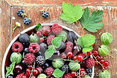 Garden berries in a bowl on wooden background Stock Photo