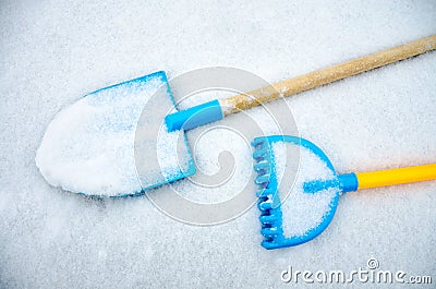 A child`s toy spade and rake left outside in the snow Stock Photo