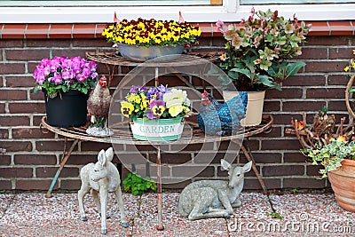 Garden decor for design. My home garden. A stone sculpture - deer figurines a souvenir from a vacation. Colorful vintage flower Stock Photo