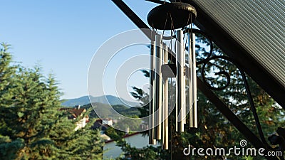 Garden decoration, wind chimes hanging under the roof of the balcony of a house. Cypress tree in the street of a neighborhood in a Stock Photo