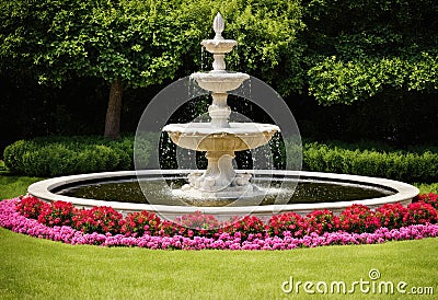 A garden fountain surrounded by blooming flowers Stock Photo