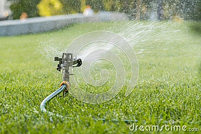 Garden irrigation system watering lawn. watering the lawn in the hot summer. Lawn sprinkler spaying water over green grass. Irriga Stock Photo