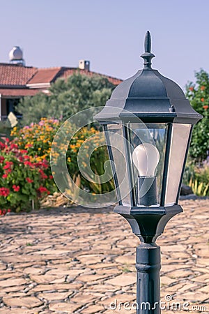Garden lantern in traditional European rural courtyard with house and flowering plants on background Stock Photo