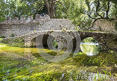 Garden of Ninfa in Italy with the bridge in cobblestones, river and trees. Editorial Stock Photo