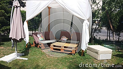 Garden palet table and chairs with a white sun tent and umbrella Stock Photo