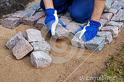 Garden path construction - worker laying granite stone pavers Stock Photo