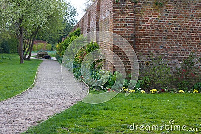 Garden scene showing path with corner of brick wall and ground cover plants Stock Photo