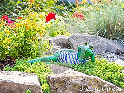 A garden sculpture of a frog lying on the floor reading a book Stock Photo