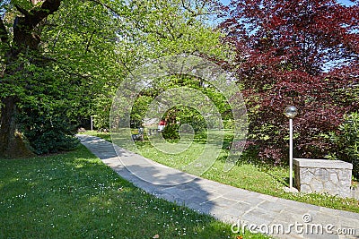 Garden with stone tiled path and street lamp in a sunny day, Italy Stock Photo