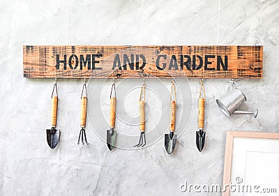 Garden tool hanging on concrete wall with wooden label Stock Photo