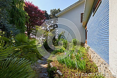 Garden and villa with stone tiled path and plants in a sunny day, Italy Stock Photo