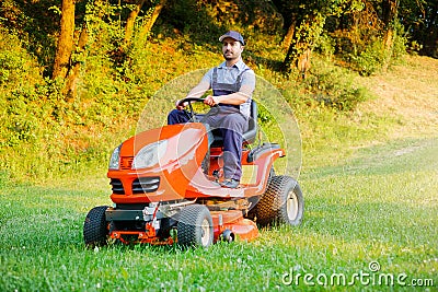 Gardener driving a riding lawn mower in garden Stock Photo