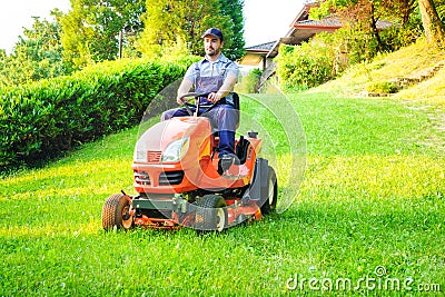 Gardener driving a riding lawn mower in garden Stock Photo