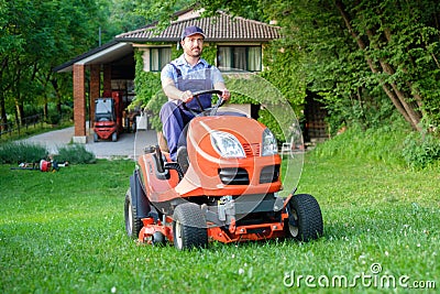 Gardener driving a riding lawn mower in garden Stock Photo