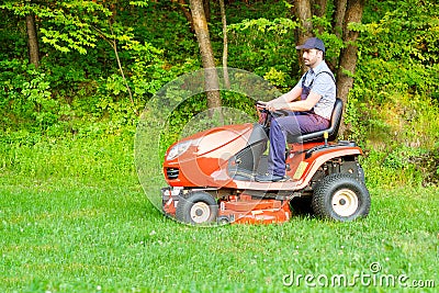 Gardener driving a riding lawn mower in garden Stock Photo