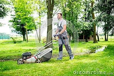 Gardener equipped with lawnmower on the job Stock Photo