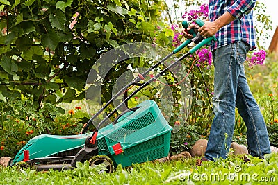 Gardener Mow Grass With Lawn Mower In Garden. Stock Photo