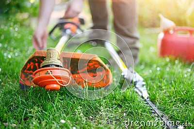 Gardener preparing grass trimmer on lawn in garden outdoors. Stock Photo