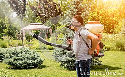 Gardener in protective mask and glasses spraying toxic pesticides trees Stock Photo