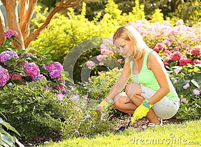 Gardening. Blonde young woman planting flowers in garden Stock Photo