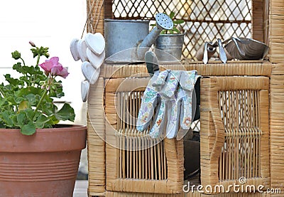 Gardening gloves and other accessories on a little outdoor wicker furniture Stock Photo