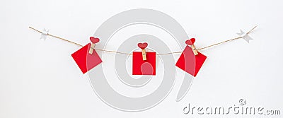 Garland with heart pins and red paper memo on rope twine on white wall, banner format. Decorations for Valentine`s Day Stock Photo