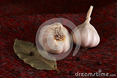 Garlic, bay leaf, black pepper on a red textile. Food background. Garlics. sliced garlic, garlic clove, garlic bulb. Stock Photo