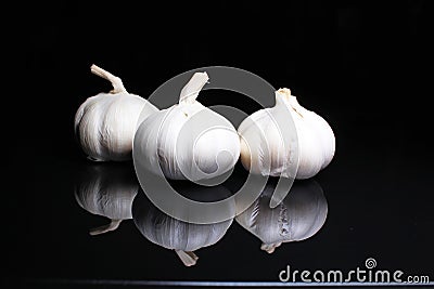 Garlic on black reflective studio background. Isolated black shiny mirror mirrored background for every concept. Stock Photo