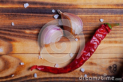 Garlic and dry red pepper on burned wooden table. Preparing for traditional rural dinner Stock Photo