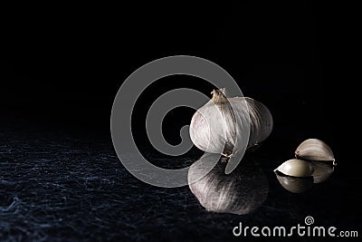 A garlic head with garlic cloves on a black and silver kitchen top background. Stock Photo