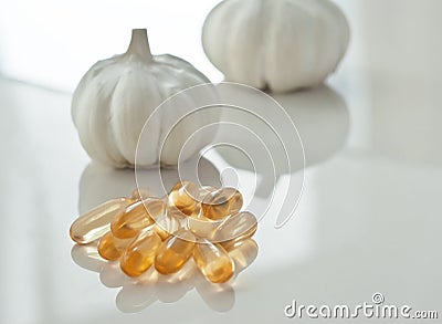 Garlic oil capsules on a white reflective surface Stock Photo