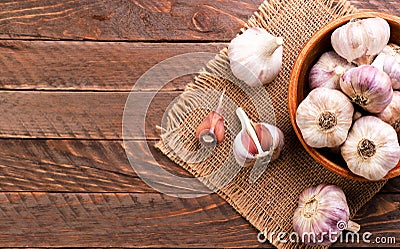 Garlic in a plate whole and a clove of garlic on a wooden background, top view. Copy space Stock Photo