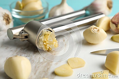 Garlic press and fresh cloves on board, closeup. Organic product Stock Photo