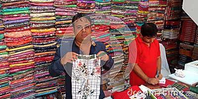 garment shopkeeper showing kids wear outfit dress into the shop Editorial Stock Photo