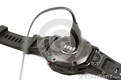 Garmin Fenix 6 Pro smart watch charge. Charging fitness tracker isolated on white background Editorial Stock Photo