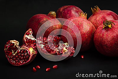 Garnet fruits and pulp on black background. Fresh pomegranate fruits and seeds close up. Stock Photo