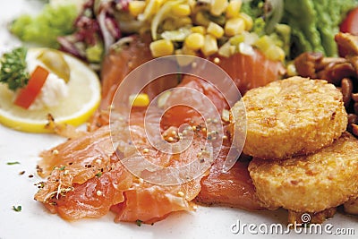 Garnished smoked salmon with motley salad and potato patties, served on plate Stock Photo