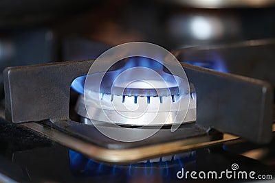Gas burner on stove with blue fire at home closeup Stock Photo