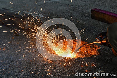 A gas cutter in production, a welder removes unnecessary metal residues with a gas cutter, sparks fly in different directions Stock Photo