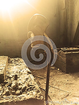 Gas mask hanging on a vertical stick in an abandoned building. Stock Photo