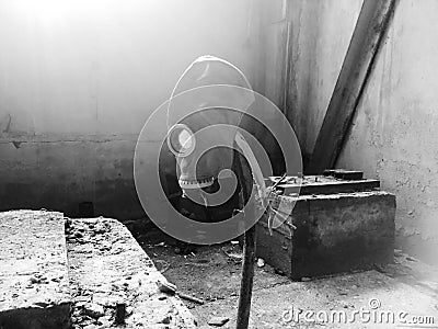 Gas mask hanging on a vertical stick in an abandoned building. Stock Photo