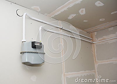 Gas meter and natural gas pipeline in room with plasterboard, drywall repair and plastering works Stock Photo